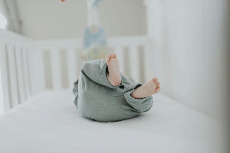 Cute baby feet in pajamas on a soft white breathable crib mattress. Perfect for children's room decor.