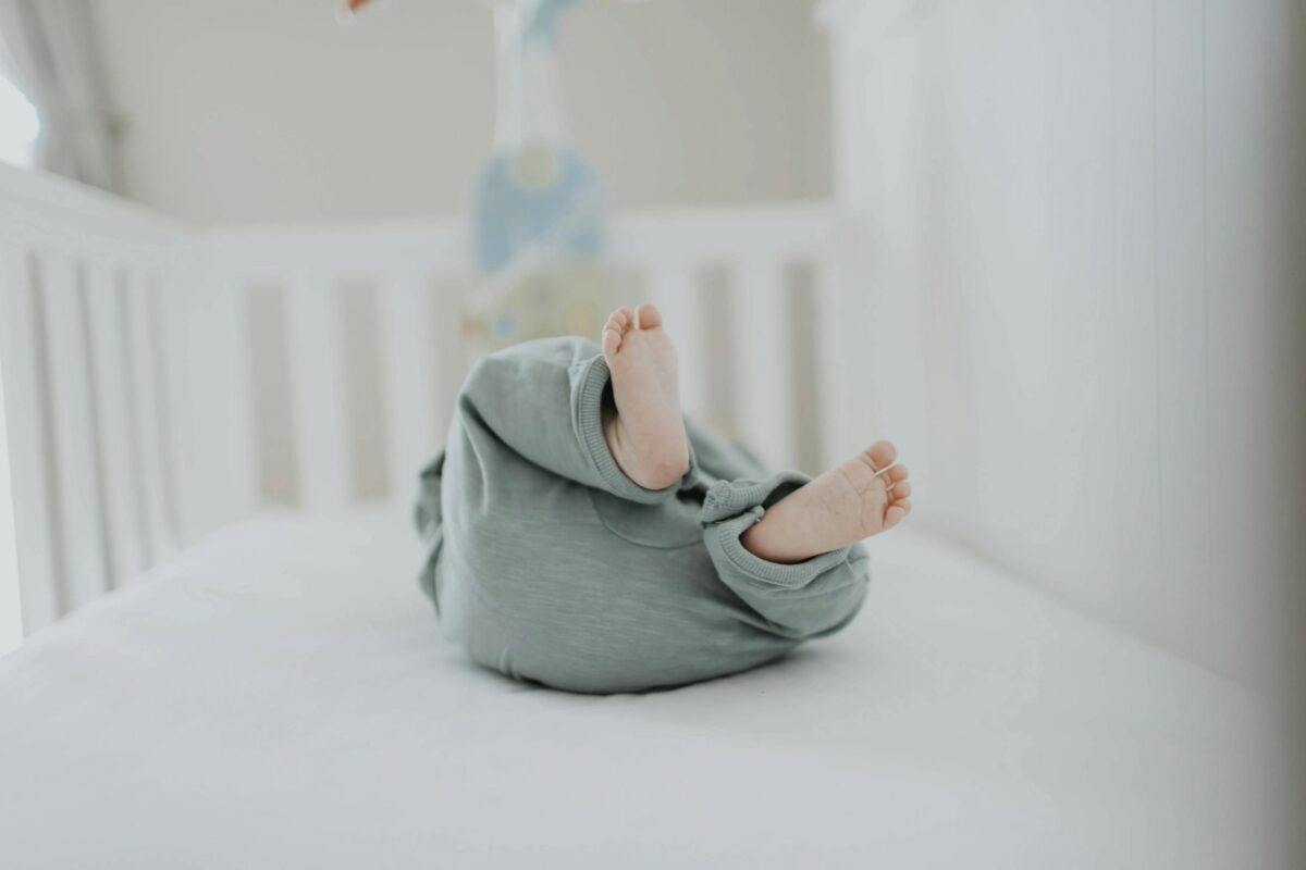 Cute baby feet in pajamas on a soft white breathable crib mattress. Perfect for children's room decor.