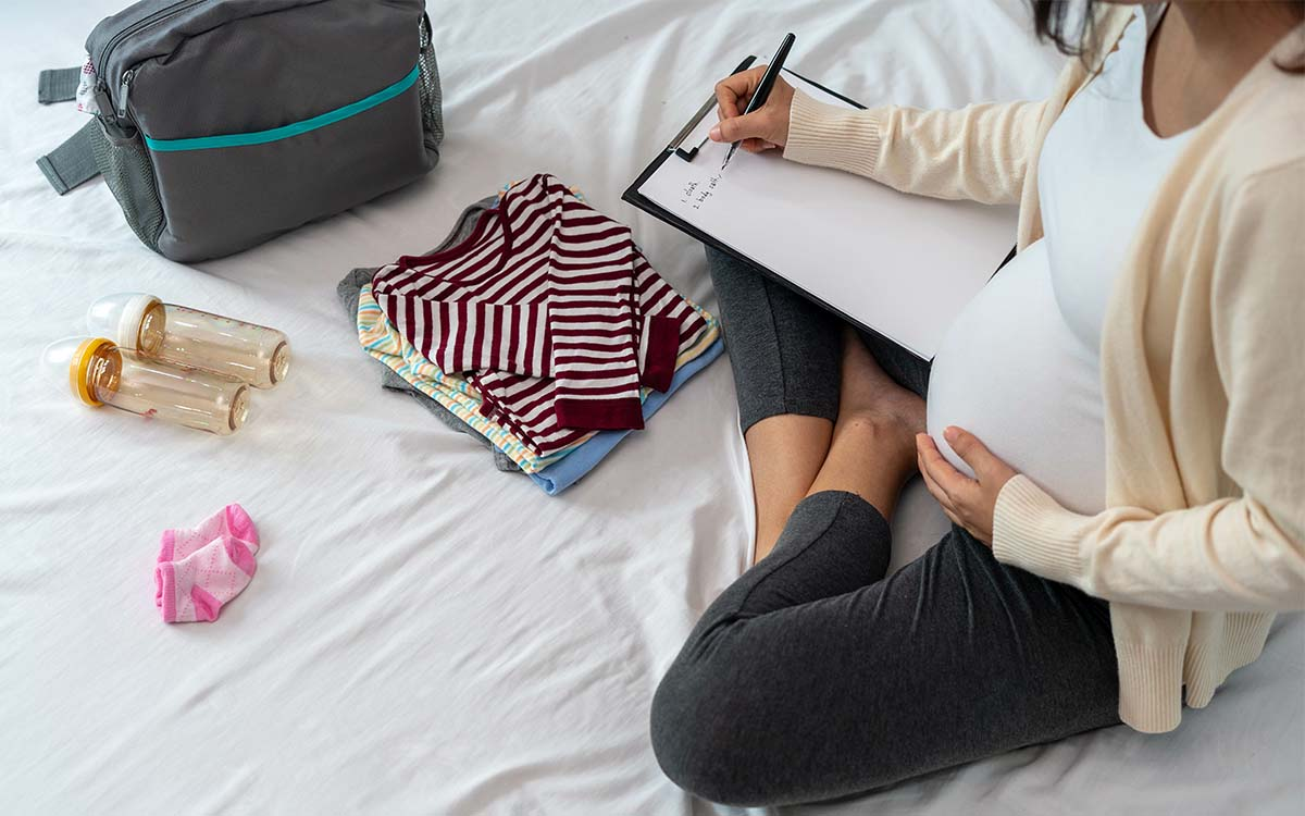 pregnant woman organizing and packing with a hospital bag checklist