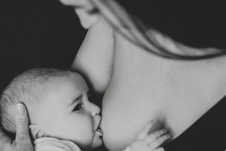 Tender black and white portrait of a mother breastfeeding her baby, showcasing motherhood and care.