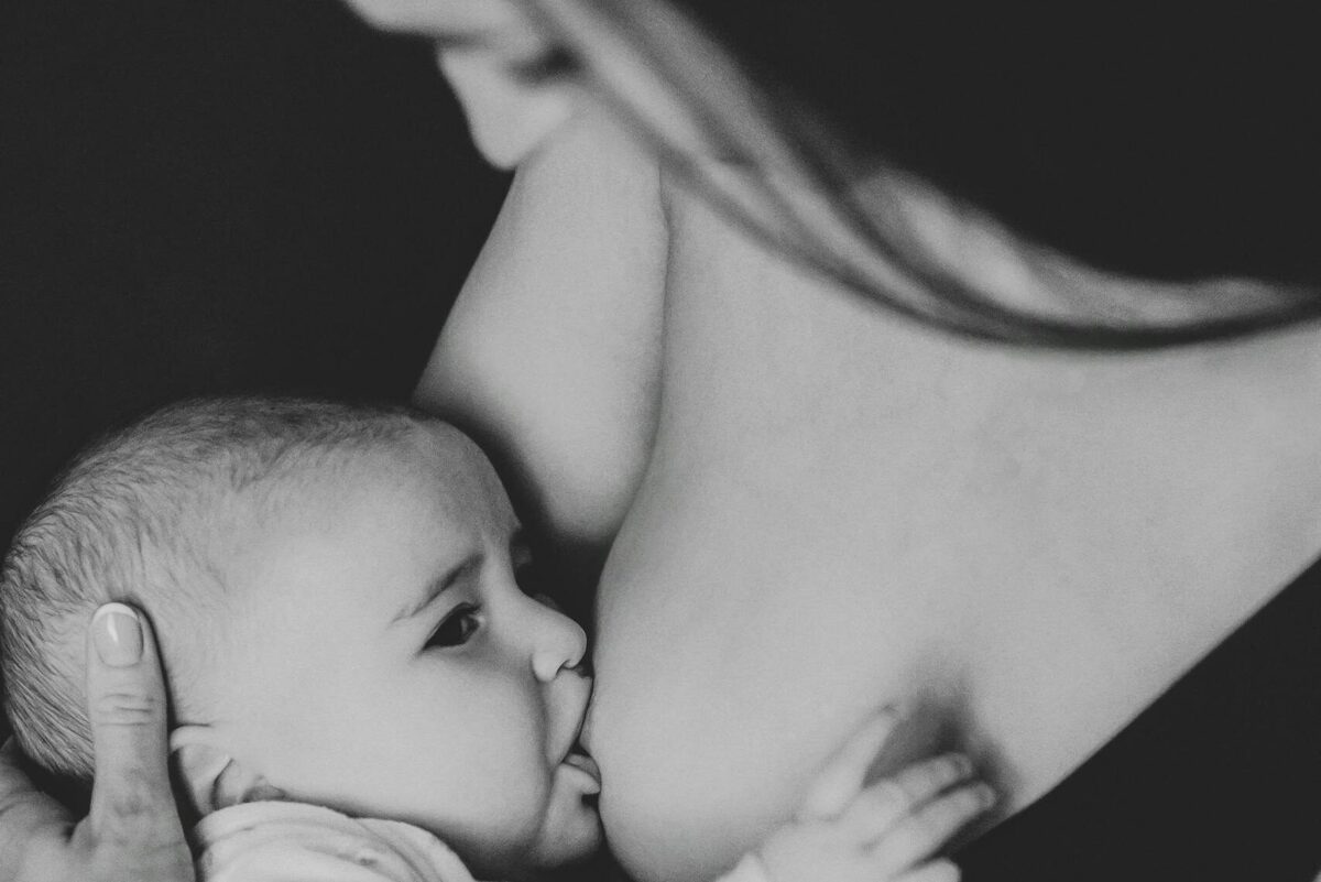Tender black and white portrait of a mother breastfeeding her baby, showcasing motherhood and care.