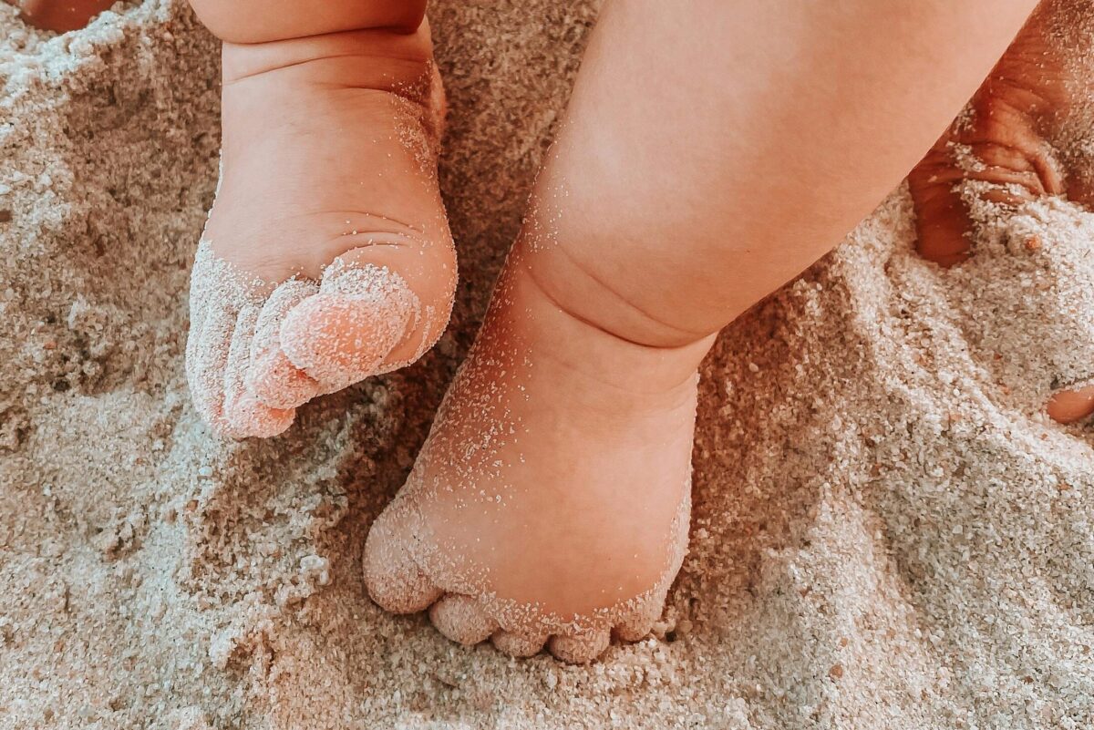 Adorable baby feet playing in the sand on a sunny beach day.
