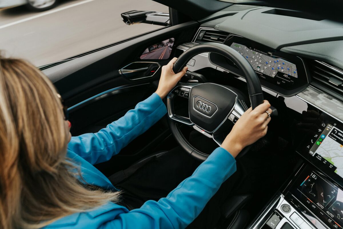 High angle view of a woman driving a modern Audi car, showcasing the dashboard and steering wheel.