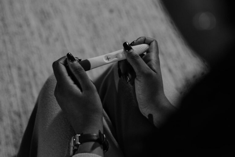 I'm pregnant now what; Monochrome image of a woman holding a pregnancy test, capturing anticipation.