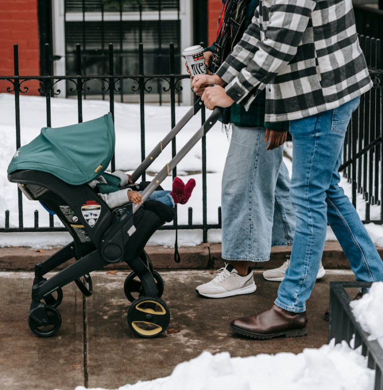 couple walking baby in doona stroller in winter
