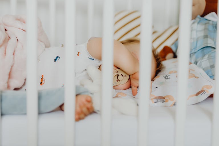 baby sleep schedules: A baby peacefully sleeping with a pacifier in a cozy crib with plush blankets.
