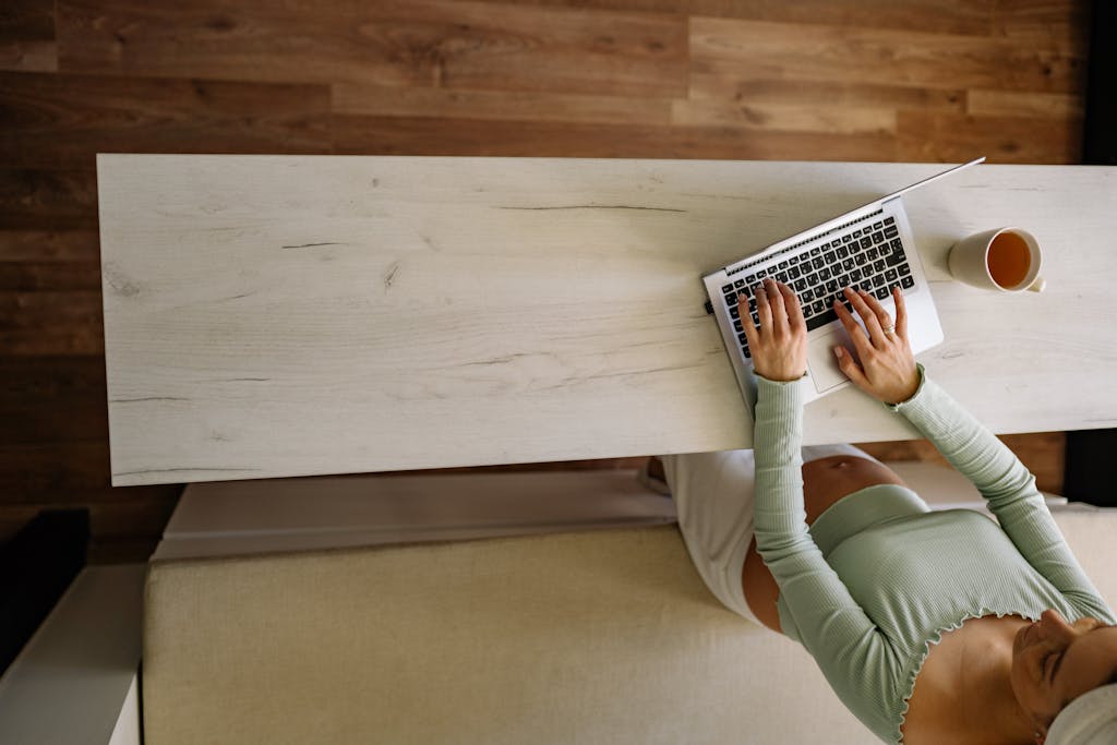 A pregnant woman working remotely from home, using a laptop with a coffee nearby. Caffeine during pregnancy