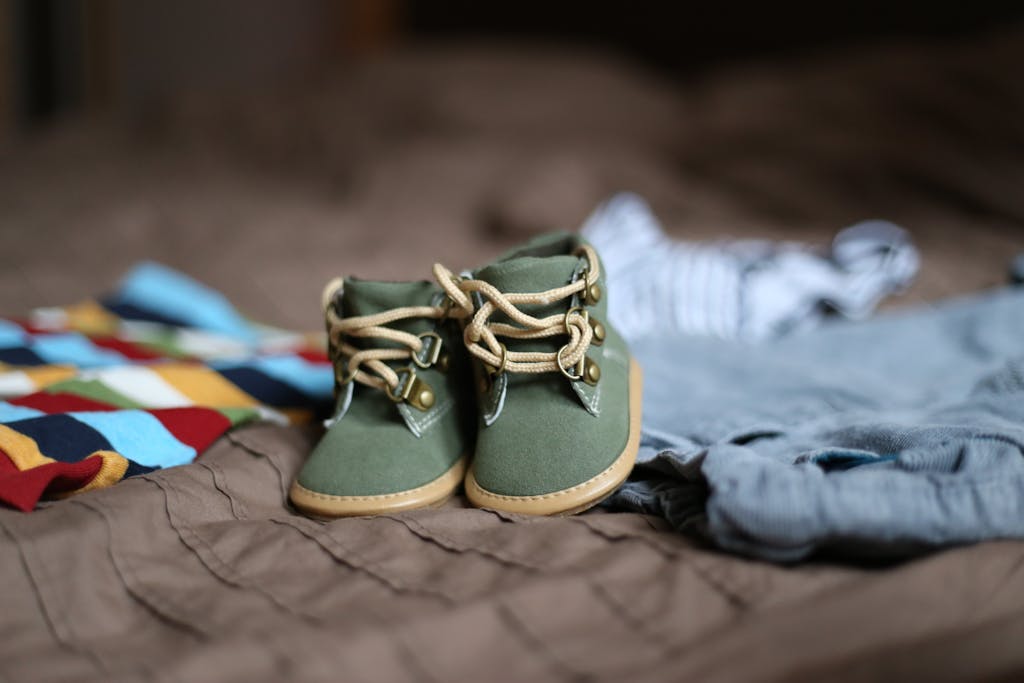 ultimate nesting checklist: Adorable green baby booties surrounded by colorful clothes, perfect for infant fashion.