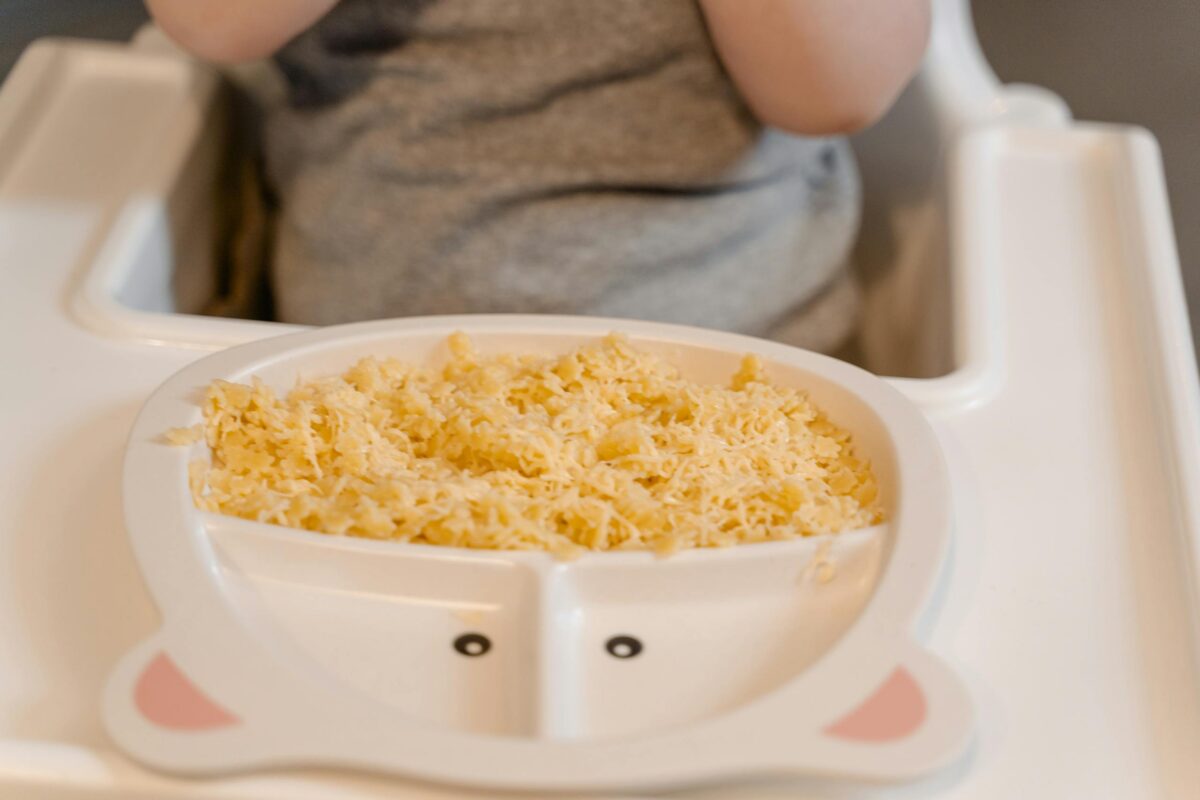 Close-up of a baby in a high chair enjoying scrambled eggs during meal time, baby-led weaning meal ideas