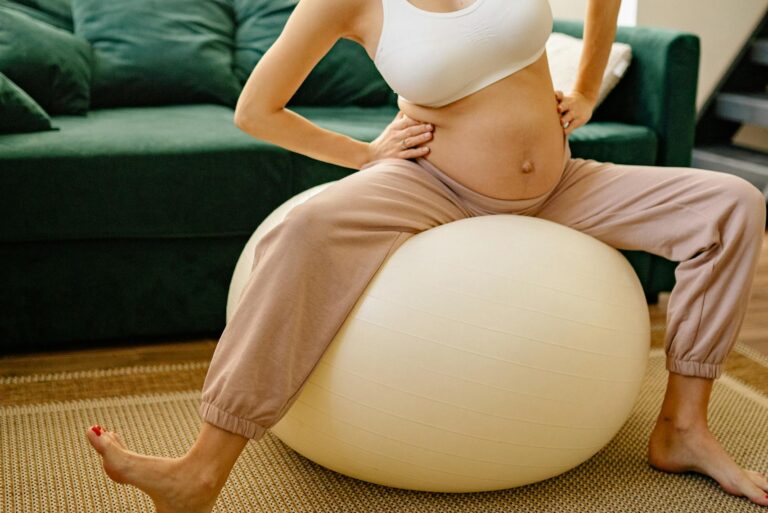 labor hacks: Expectant mother enjoying a fitness routine indoors on a yoga ball.