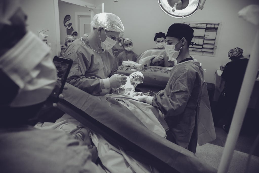 Medical team delivering a newborn via cesarean section in a hospital operating room. - birth plan