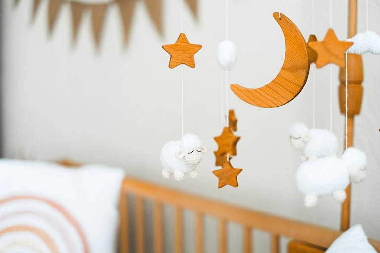 Nursery theme ideas: Wooden crib mobile featuring stars, a crescent moon, and fluffy sheep for a cozy baby nursery.